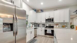 A modern kitchen with stainless steel appliances, white cabinetry, and a tiled backsplash. - Shuttle Launch Views! Escape 9 Mi to Cocoa Beach (Rockledge)