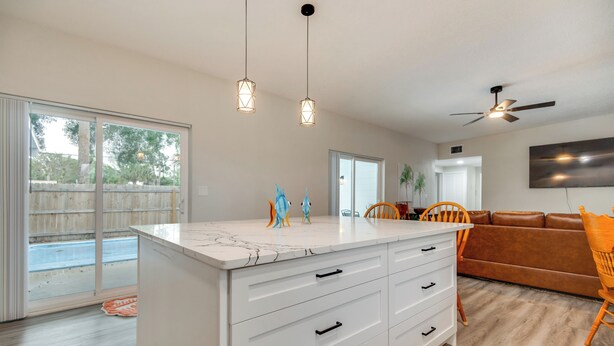 A modern kitchen with a marble countertop, white cabinetry, and pendant lighting. - Shuttle Launch Views! Escape 9 Mi to Cocoa Beach (Rockledge)