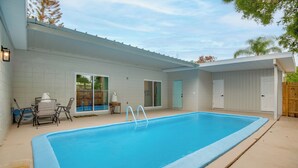 A rectangular swimming pool with a white deck, a covered patio area, and a door leading to a covered garage. - Shuttle Launch Views! Escape 9 Mi to Cocoa Beach (Rockledge)