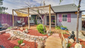 A backyard with a wooden deck, a pergola, a statue, and a house with pink shutters. - Historic District Studio, 10 Mi to Balloon Fiesta (Albuquerque)