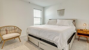 Ein Schlafzimmer mit Bett, Stuhl, Nachttisch und einer Pendelleuchte.