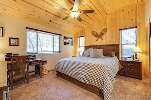 A bedroom with a bed, desk, chair, and a ceiling fan.