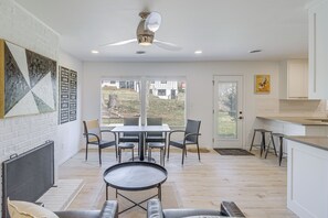 Eine moderne Küche mit weißen Schränken, einem Essbereich mit Tisch und Stühlen sowie einem Deckenventilator.