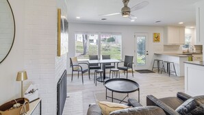 A modern living room with a fireplace, a dining area, and a kitchen. - Overland Park Home Near Dtwn w/ Easy Hwy Access (Overland Park)