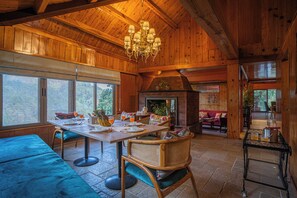 Un interior de madera con comedor, asientos y chimenea.