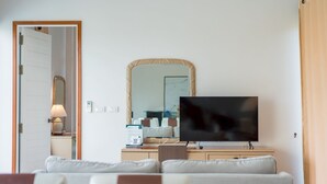 Una sala de estar con televisión, espejo, sofá y una puerta que da a otra habitación.