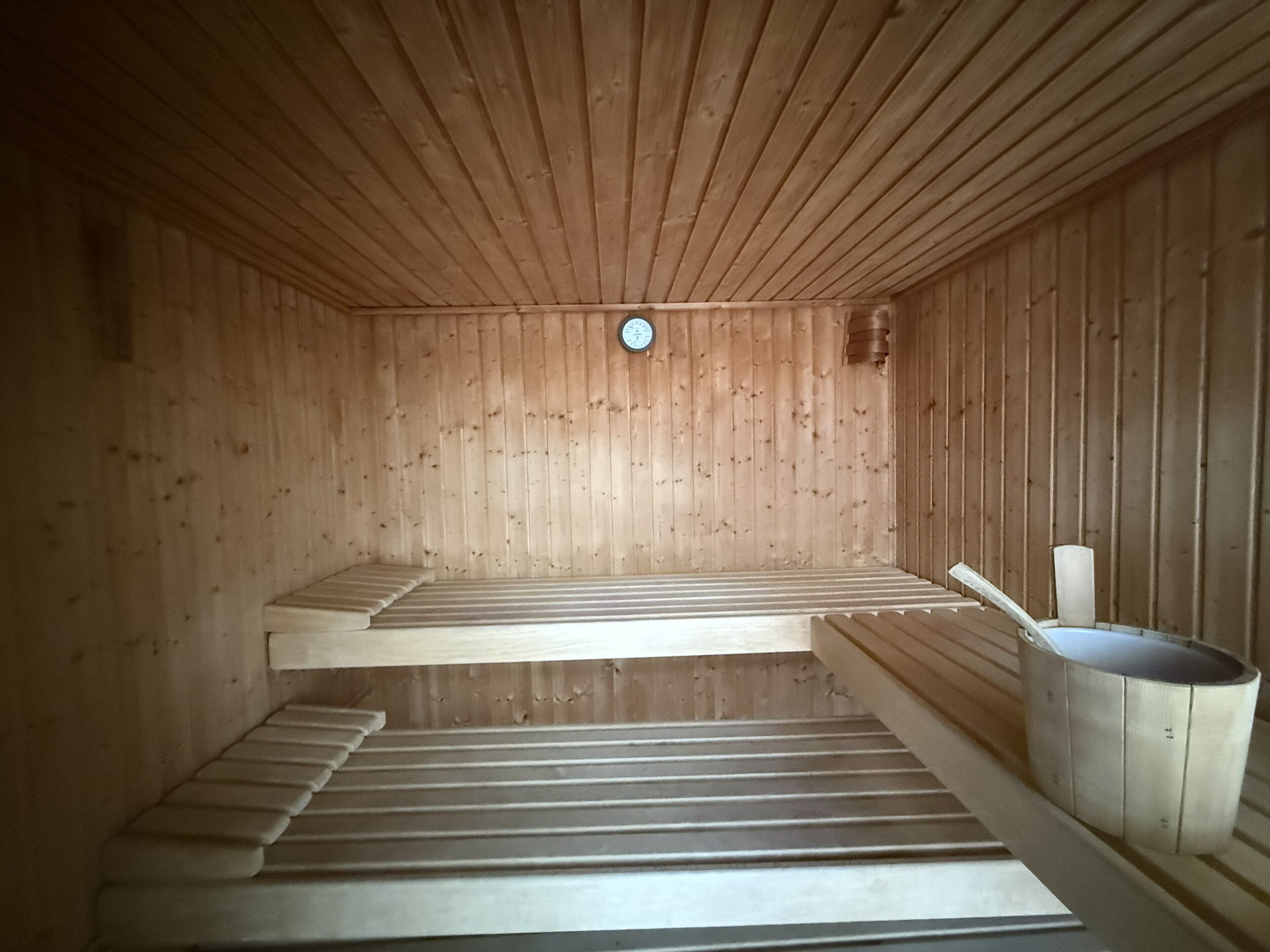 Eine Sauna mit Holzwänden, Bänken und einem Eimer.