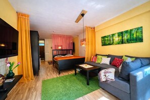 Een moderne kamer met een bed, bank, televisie en kunstwerken.