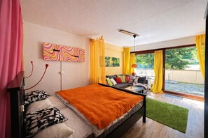 Een slaapkamer met een bed, een bank, een raam met gordijnen en een schilderij aan de muur.