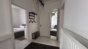 Een moderne hotelkamer met een bed, een klein bankje, een kapstok en een spiegel.
