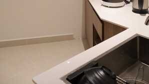 Una cocina con ventana, un lavamanos, un hervidor y una cafetera.