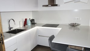 Een moderne keuken met witte kasten, een roestvrijstalen spoelbak en een zwart aanrecht.