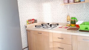 Une cuisine équipée d’un réfrigérateur, d’une cuisinière, de meubles en bois et d’un dosseret carrelé.