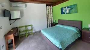 Une chambre à coucher comprenant un lit, un bureau, une chaise, un téléviseur et un climatiseur.