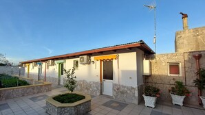 Un bâtiment doté d’un patio carrelé, de murs en pierre et de plantes en pot.