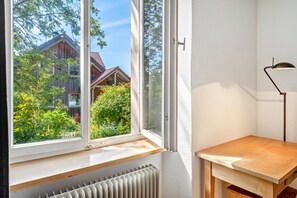 A room with a large window, a radiator below, and a wooden table.