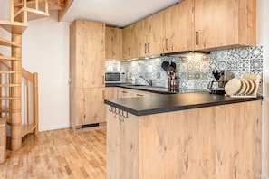 A kitchen with wooden cabinets, a microwave, a coffee maker, and a knife block. - 'maisonette 5' – Spacious Apartment in Kürnberg: Alpine Views, Private Terrace & Balcony, Parking, Wi-Fi (Schopfheim)
