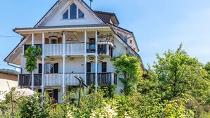 A multi-story building with balconies, a chimney, and a garden in front.