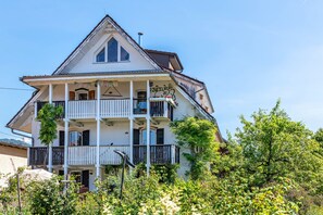 A multi-story building with balconies, a chimney, and a garden in front.