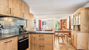 A kitchen with wooden cabinets, a built-in oven, and a dining area with wooden furniture.