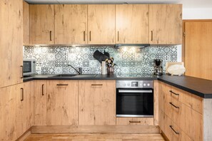A kitchen with wooden cabinets, a microwave, a coffee maker, and a tiled backsplash.