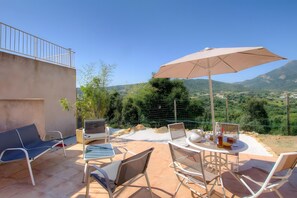 An outdoor patio with a table, chairs, and a large umbrella.