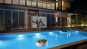 A swimming pool with a built-in bar area, a large screen for entertainment, and a covered patio. - Alaya Stays Parinita Farm 4 BHK Villa (Faridabad)