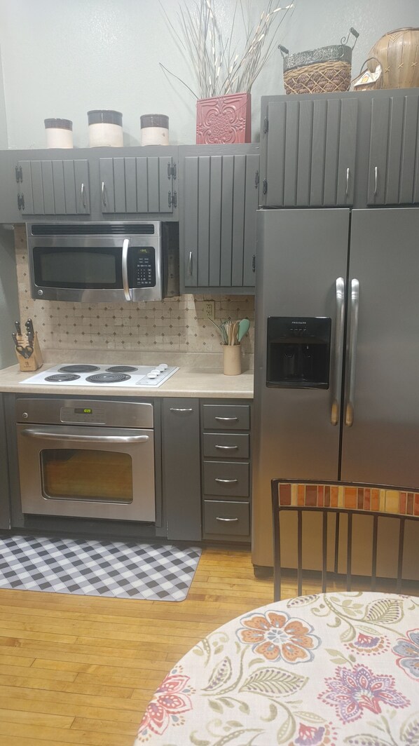Une cuisine équipée d’un four à micro-ondes, d’une cuisinière, d’un four, d’un réfrigérateur et de placards.