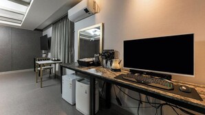 Ein modernes Hotelzimmer mit Schreibtisch, Computer und Flachbildfernseher.