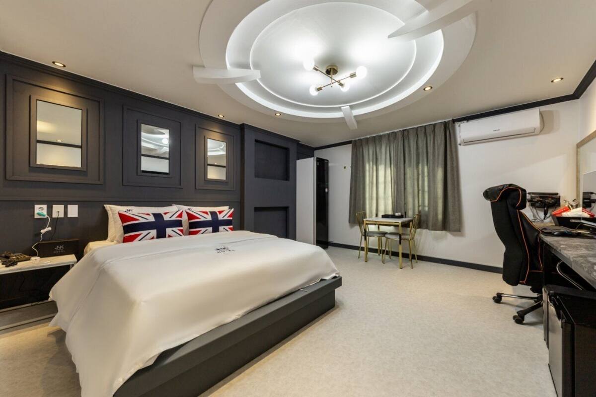 Une chambre d’hôtel moderne équipée d’un lit, d’un bureau, d’une chaise et d’une grande fenêtre avec des rideaux.