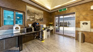 Eine Hotelhalle mit einer Rezeption, einer Kaffeemaschine, einer Mikrowelle, einem Mülleimer und einem großen, gerahmten Bild an der Wand.