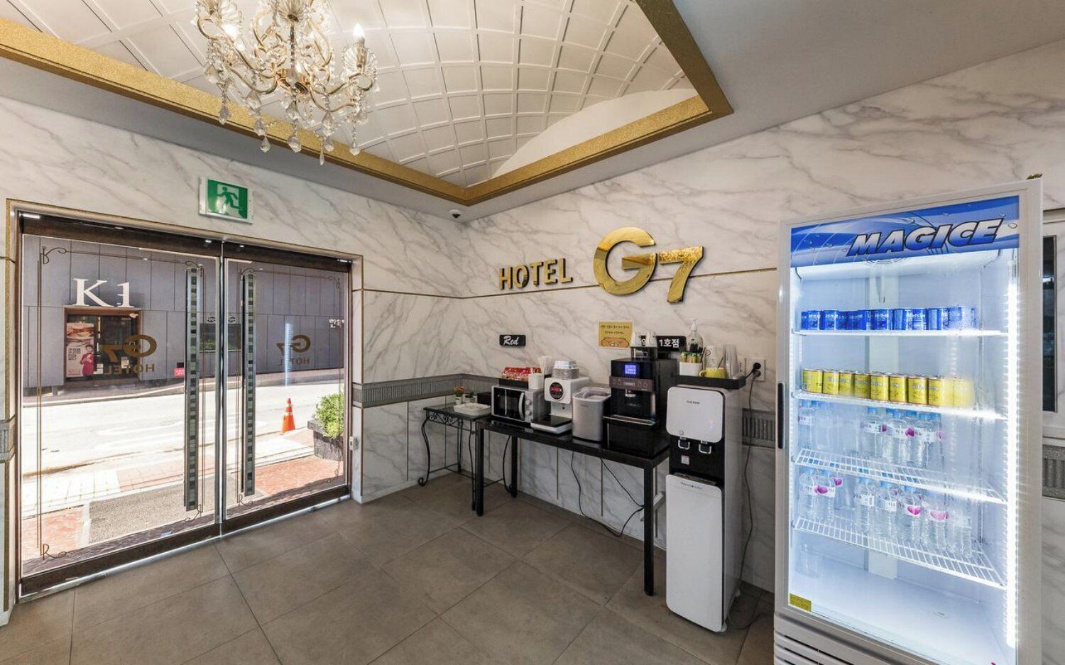 Un vestíbulo de hotel con mostrador de recepción, minibar, candelabro y máquina expendedora.