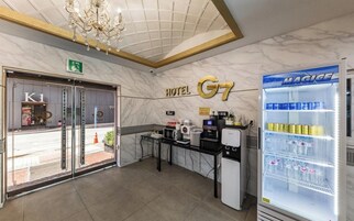 Un vestíbulo de hotel con mostrador de recepción, minibar, candelabro y máquina expendedora.