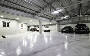 A spacious indoor parking area with multiple cars, a visible hotel sign, and a clean, reflective floor.
