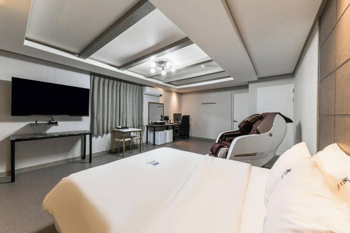 Une chambre d’hôtel équipée d’un lit, d’un bureau, d’une chaise, d’une télévision et d’un fauteuil de massage.