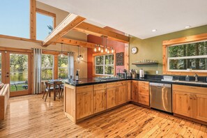 Una cocina moderna con armarios de madera, lavavajillas y una zona de comedor con mesa y sillas.