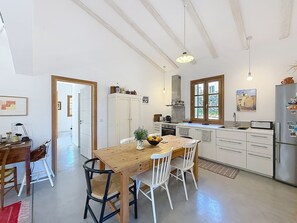 A kitchen with a wooden table, white chairs, a refrigerator, and a window with a view. - Very nice apartment in a charming village house, village of Pigna (Pigna)