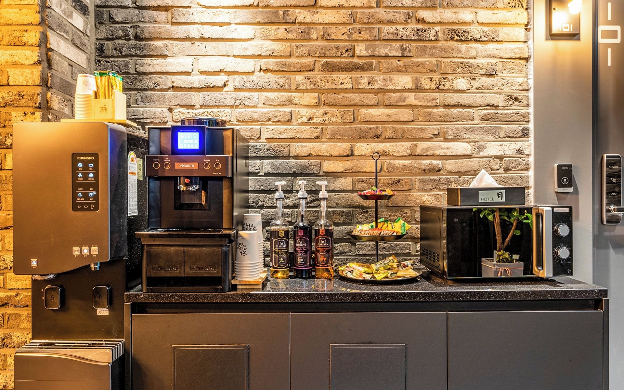 Eine Hotelbar mit einer Kaffeemaschine, einer Minibar und einer Auswahl an Snacks.