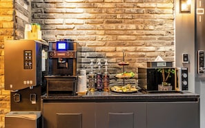 Zona de bar d'hotel amb una màquina de cafè, un minibar i una selecció de llaminatures.