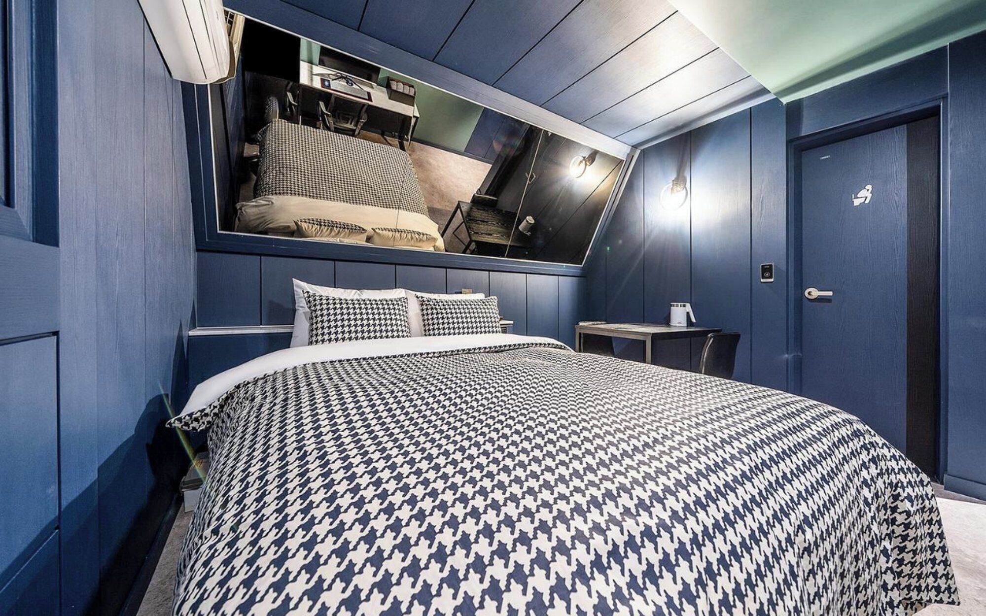 Un dormitorio con una cama grande, una mesita de noche, un espejo y una puerta.
