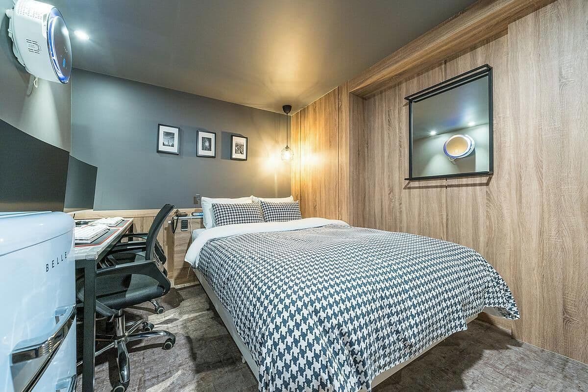 Un dormitorio con cama, escritorio, silla y un ventanal grande.