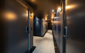 Ein Hotelgang mit Türen, eingelassener Beleuchtung und Holzboden.