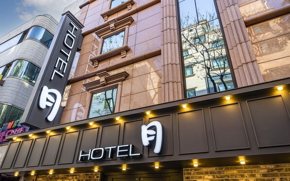 Eine Hotelscheibe mit einem gut sichtbaren 'HOTEL'-Schild, großen Fenstern und einem modernen architektonischen Design.