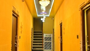 Un corridoio con pavimento a scacchi, un lampadario e porte su entrambi i lati.