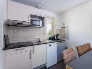 A compact kitchen with white cabinets, a microwave, a coffee maker, and a dishwasher. - Beautiful apart for 5, near the lake (Lacanau)