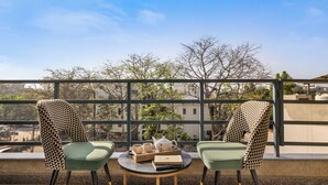 A balcony with two chairs, a table, and a tray with a teapot, cups, and books.