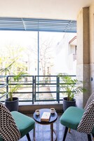 A balcony with two chairs, a table, and two potted plants.