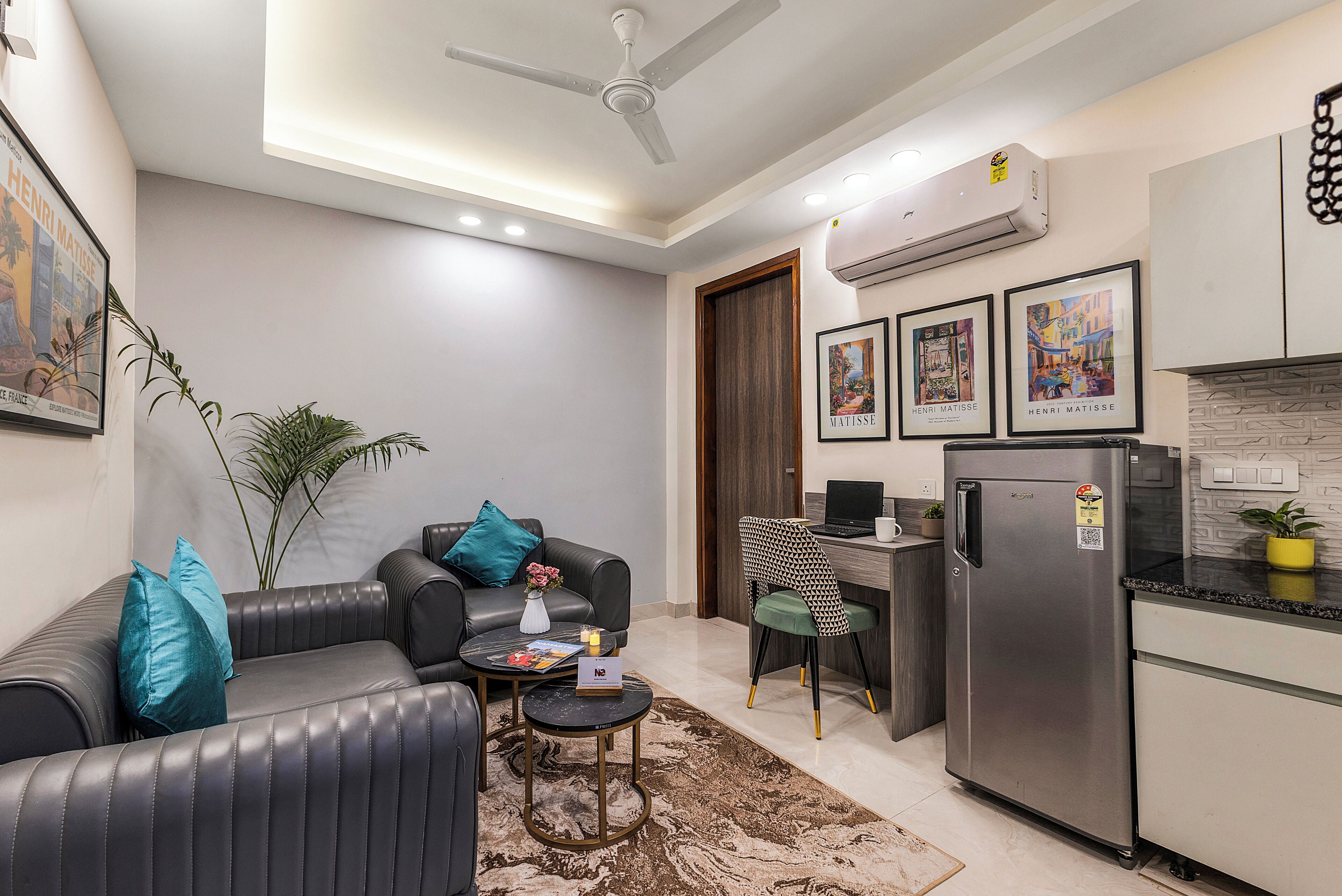 A modern living room with a sofa, coffee table, and a dining area with a refrigerator.