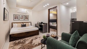 A modern hotel room with a bed, a desk, a sofa, and a small table with a plant.