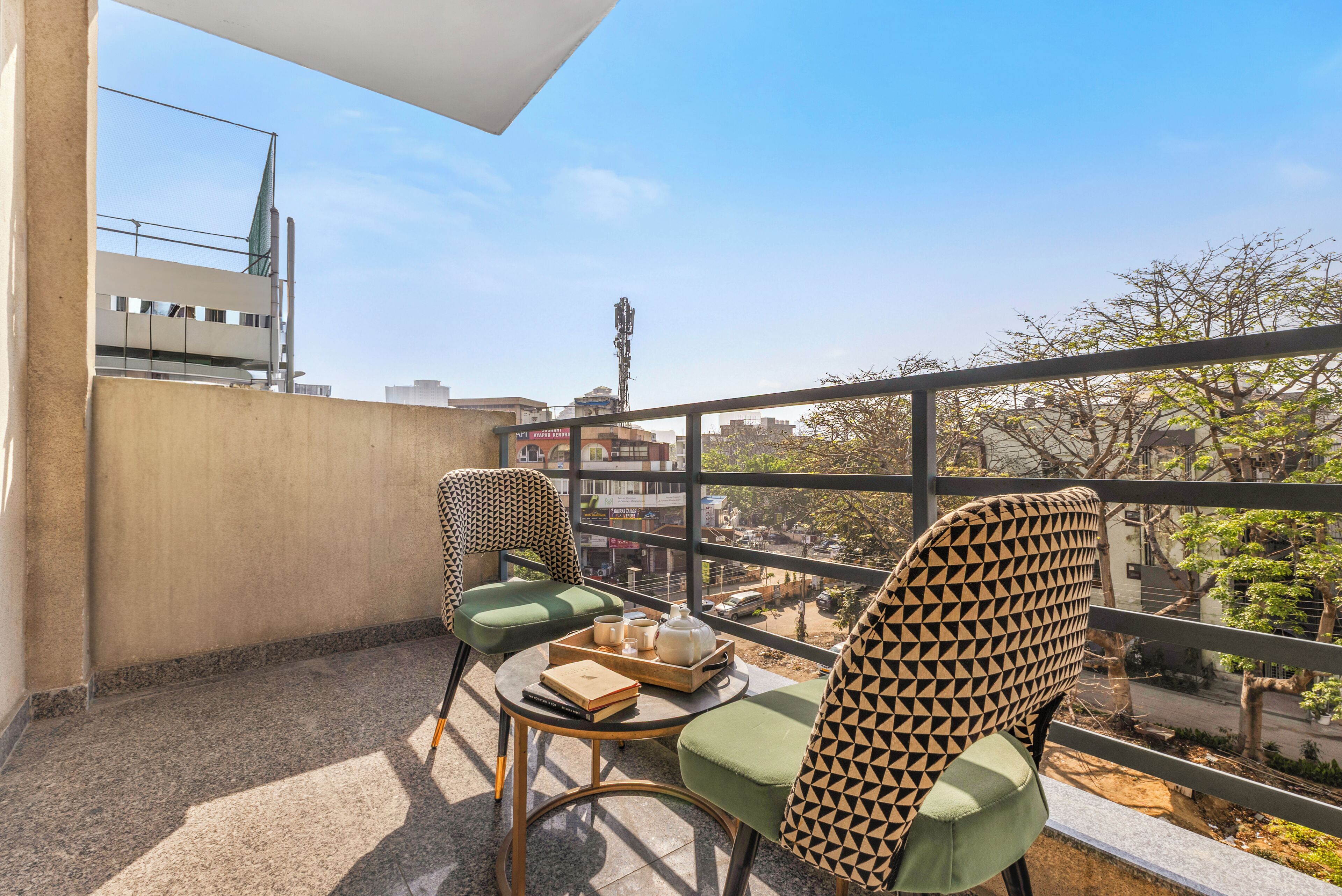A balcony with two chairs, a small table with a tray, and a view of the cityscape.